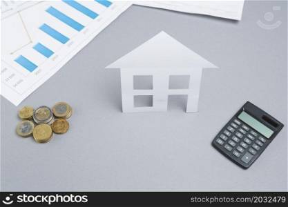 stacked coins paper cutout house with calculator business desk