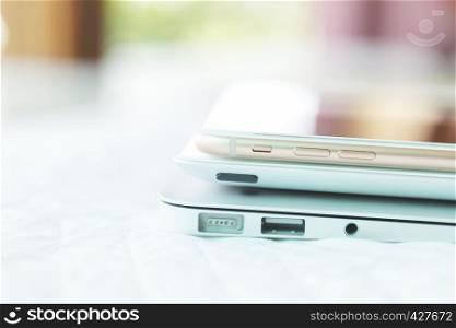 Stacked of digital devices, laptop, tablet and mobile on table in office with blurred background. Network connection technology concept. E-commerce and online business.
