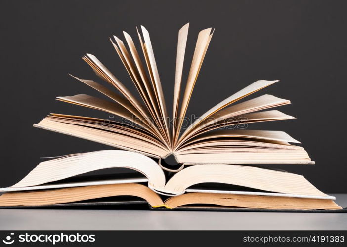 stacked open books on dark gray background