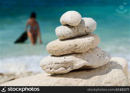 stacked pebbles on the beach, woman at blurred backgrond. stacked pebbles on the beach