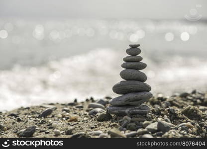 Stacked sea stones. Sea on the background. Contra light