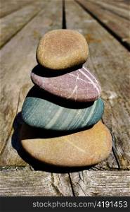 Stacked smooth stones on a wooden deck.