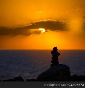 Stacked stones for a wish on Mediterranean sunset at Balearic islands