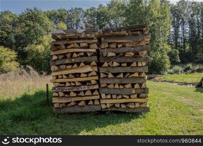 Stacked wood logs for drying in a Belgian meadow, pile of logs.
