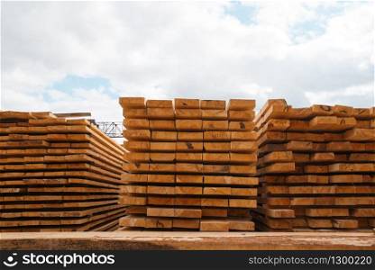 Stacks of boards on timber mill warehouse outdoor, nobody, lumber industry, carpentry. Wood processing on factory, forest sawing in lumberyard, sawmill. Stacks of boards on timber mill warehouse