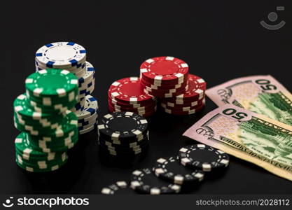 Stacks of poker chips and dollar bills on black background. Poker concept, chips and money.