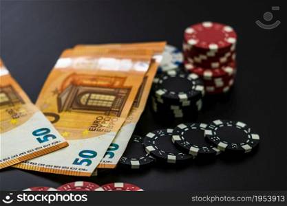 Stacks of poker chips and EURO bills on black background. Poker concept, chips and money
