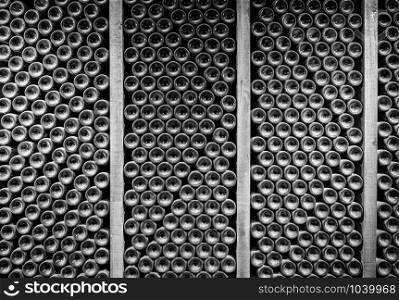 Stacks of wine bottles laying flat in wooden racks in old wine cellar or cave. Bottoms of thousands of bottle of wine in old wine-cellar