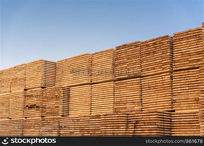 Stacks of wood boards under the blue sky. Outdoor wood storage. Wood-working industry