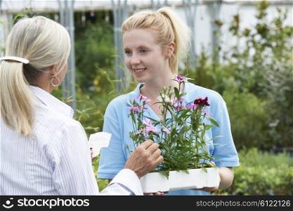 Staff Giving Plant Advice To Female Customer At Garden Center