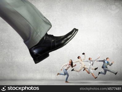 Staff reduction concept. Big businessman foot kicking businesspeople running away