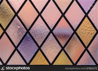 Stained glass with multi colored diamond pattern as background pink violet tone