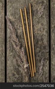 stainless metallic golden straws wooden background