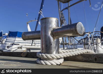 stainless steel bollard on the dock against background of yachts