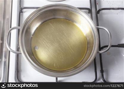 Stainless steel metal pan with olive oil prepared for cooking on a gas stove