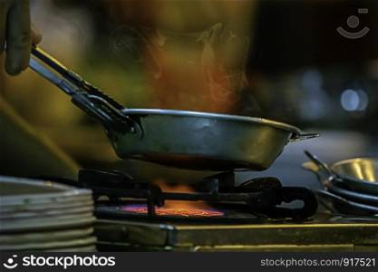 Stainless steel pan on the stove with a yellow flame.