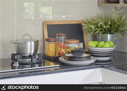Stainless steel pot and pasta jars on black granite top counter