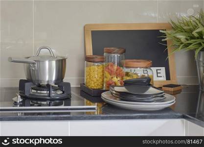 Stainless steel pot and pasta jars on black granite top counter