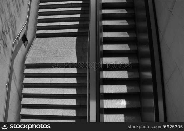 Staircase steps with handrail and escalator. Black and white.