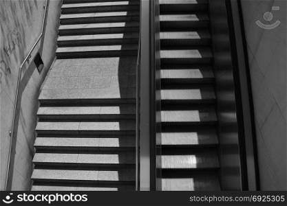Staircase steps with handrail and escalator. Black and white.