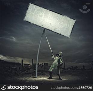 Stalker in gas mask. Man in gas mask and camouflage pulling blank banner. Place for text
