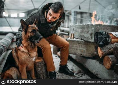 Stalker, post-apocalypse soldier feeding a dog. Post apocalyptic lifestyle on ruins, doomsday, judgment day. Stalker, post-apocalypse soldier feeding a dog