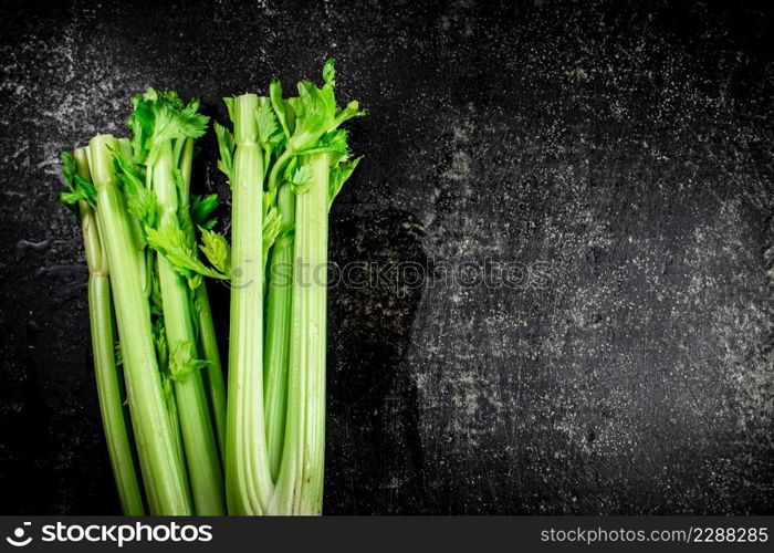 Stalks of fresh celery on the table. On a black background. High quality photo. Stalks of fresh celery on the table.