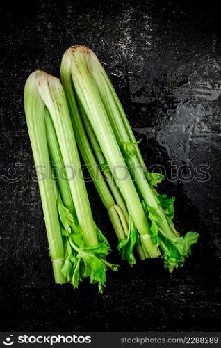 Stalks of fresh celery on the table. On a black background. High quality photo. Stalks of fresh celery on the table.