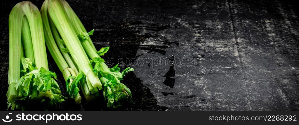 Stalks of fresh celery on the table. On a black background. High quality photo. Stalks of fresh celery on the table.