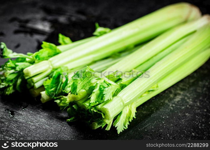 Stalks of fresh celery on the table. On a black background. High quality photo. Stalks of fresh celery on the table.