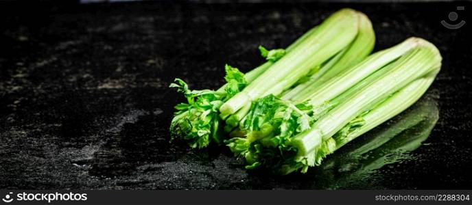 Stalks of fresh celery on the table. On a black background. High quality photo. Stalks of fresh celery on the table.