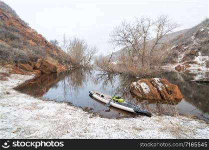 stand up paddleboard in snow blizzard on a mountain lake - Horsetooth Reservoir in northern Colorado, training, fitness and recreation concept