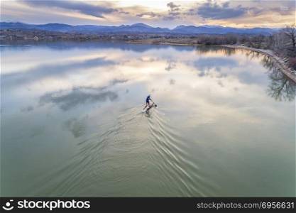 stand up paddleboard on lake - aerial view. paddling stand up paddleboard at dusk on a kae of foothills of Rocky Mountain in Colorado, early spring scenery, aerial view