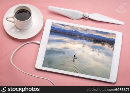 stand up paddleboard on lake - aerial view. paddling stand up paddleboard at dusk on a calm lake at foothills of Rocky Mountain in Colorado, reviewing aerial image on a digital tablet with a cup of coffee