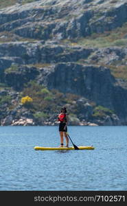 Stand up paddleboarding on lake. Watersport on lake. Tourist outdoor activity at Lagoa Comprida, Serra da Estrela National Park in Portugal.