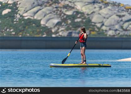 Stand up paddleboarding on lake. Watersport on lake. Tourist outdoor activity at Lagoa Comprida, Serra da Estrela National Park in Portugal.