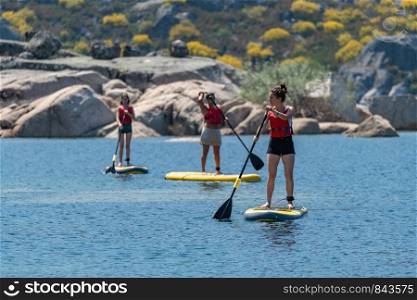 Stand up paddleboarding on lake. Watersport on lake. Tourist outdoor activity at Lagoa Comprida, Serra da Estrela National Park in Portugal.