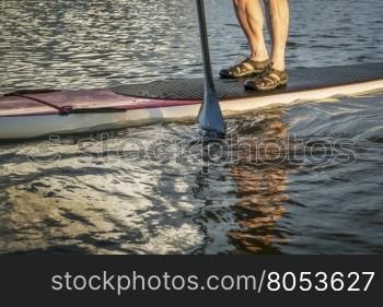 stand up paddling abstract - male feet on a paddleboard