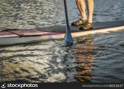 stand up paddling abstract - male feet on a paddleboard