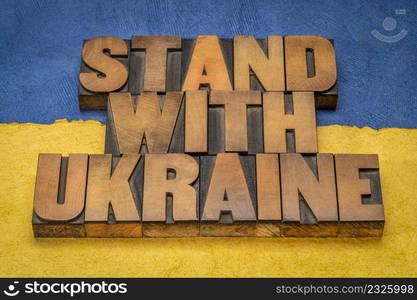 stand with Ukraine - words in vintage letterpress wood type against blue and yellow paper background in colors of Ukrainian national flag, help and support concept