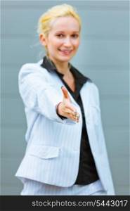 Standing at office building modern business woman stretches out hand for handshake&#xA;