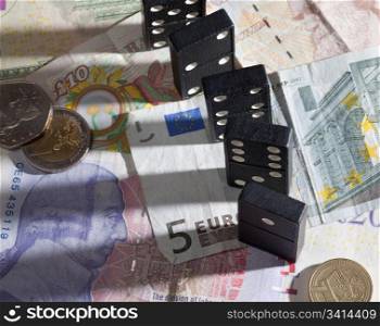 Standing dominoes with harsh shadows on pound, euro and dollar bank notes illustrating banking crisis
