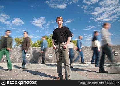 standing man among moving pedestrians