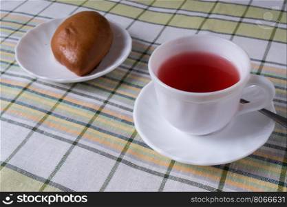 standing on the table white Cup with fruit tea and a plate of pie. White Cup with fruit tea and cake in the plate