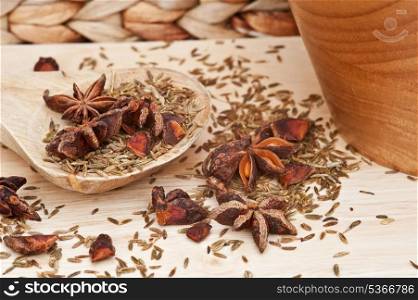 Star anise and cumin seed herbs in kitchen setting with rustic wooden utensils