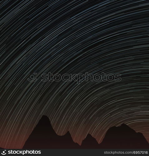 Star trails and far rocks. Abstract background with star trails in the night sky and rocks silhouettes.