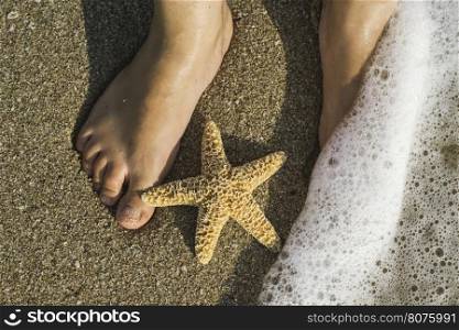 Starfish and feet on the beach. Sea waves