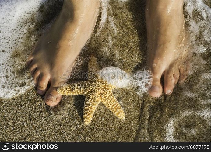 Starfish and feet on the beach. Sea waves