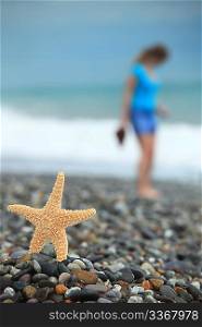 Starfish and young girl on stone seacoast