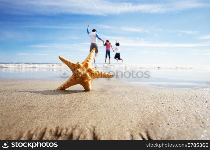 Starfish In Foreground As Father Plays With Children In Sea